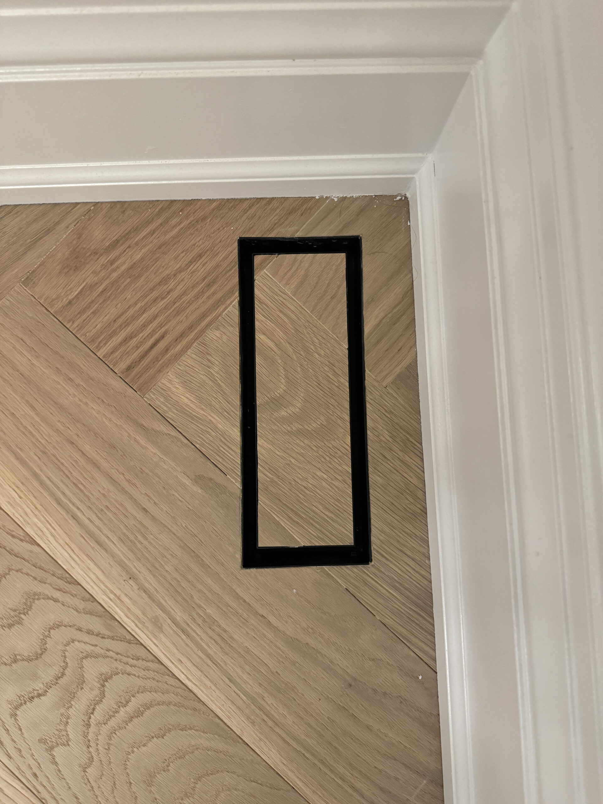 Flush vent with baseboards and herringbone flooring