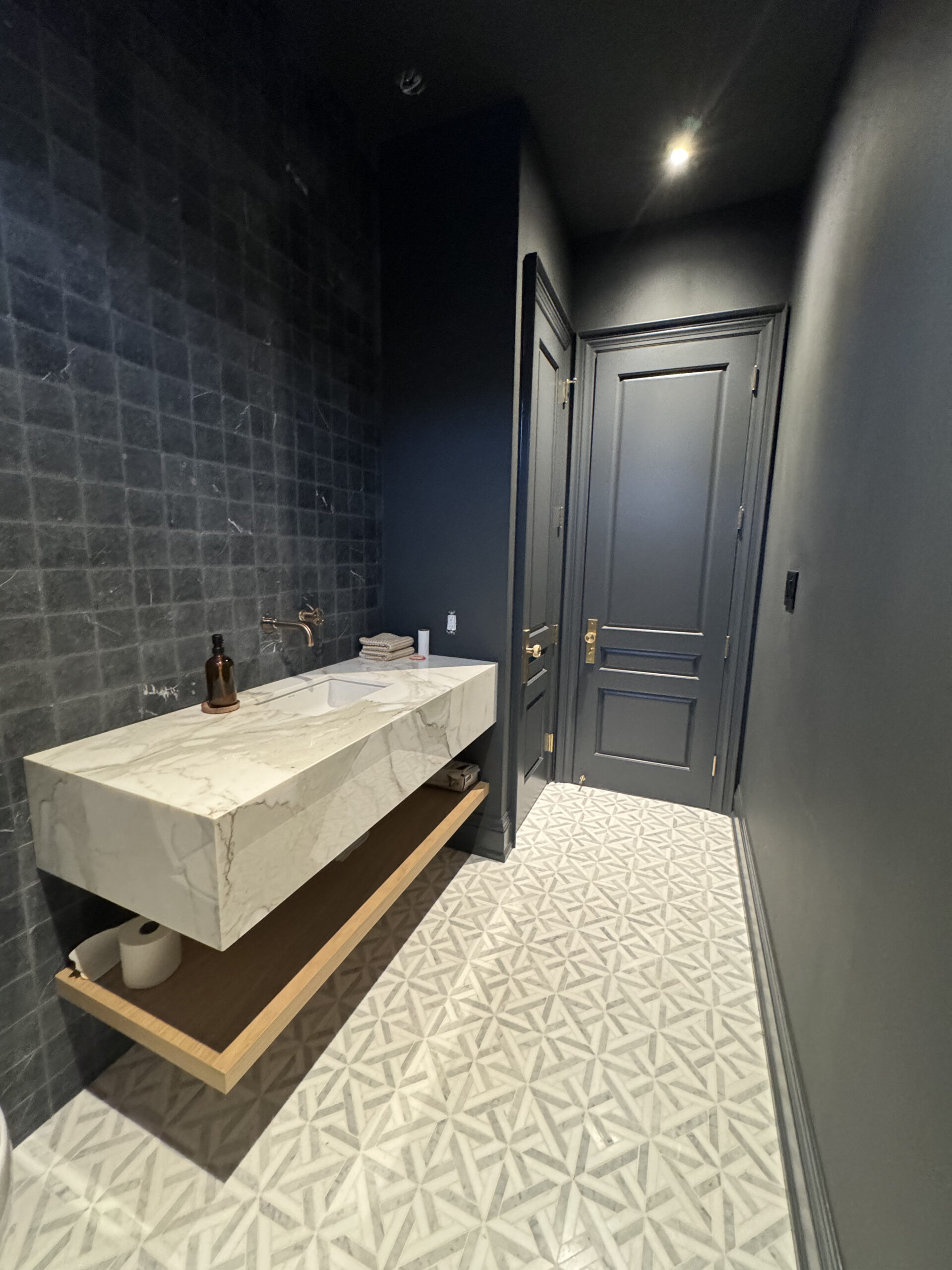 Modern powder room with black tile and marble vanity
