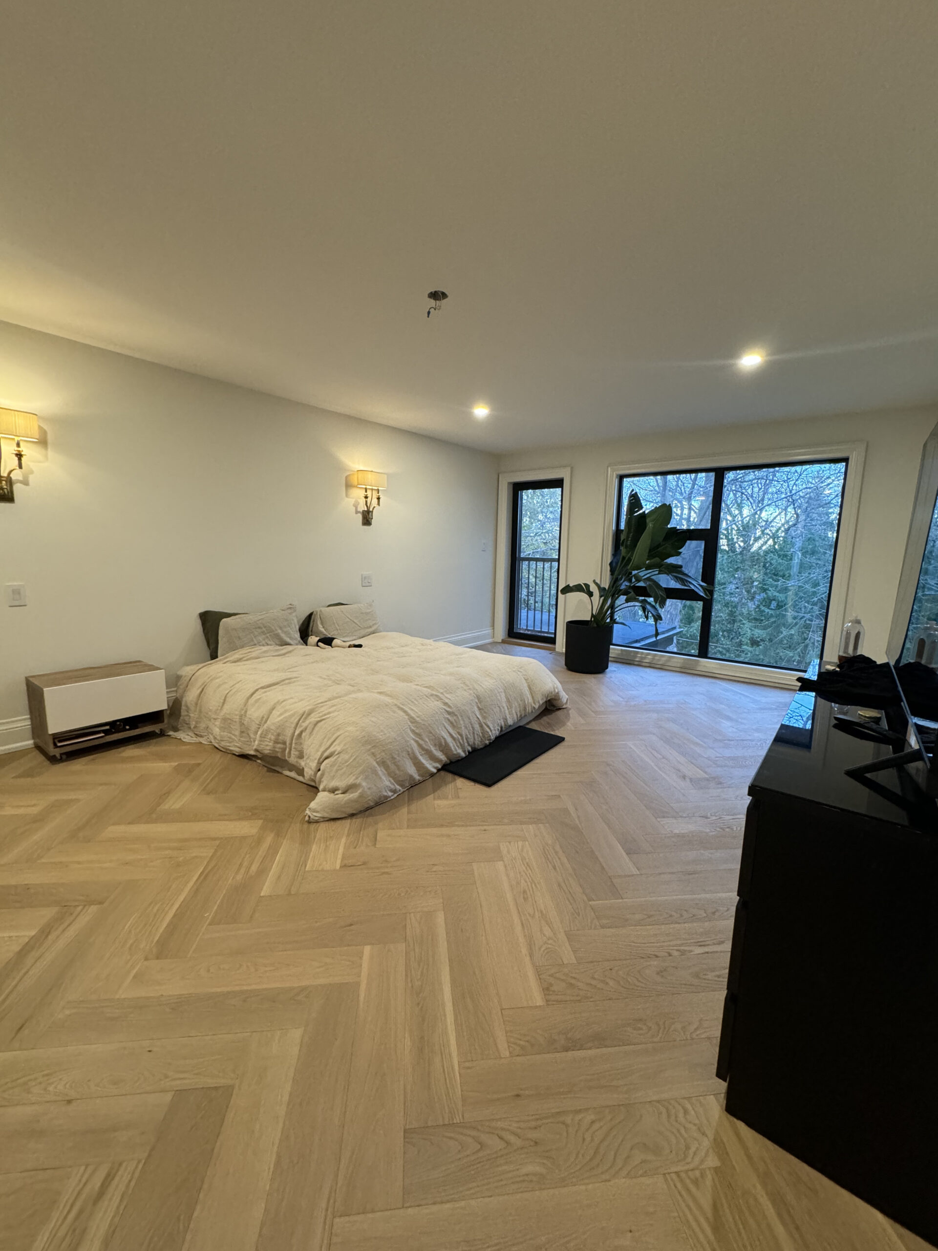 Spacious bedroom herringbone floors and large windows