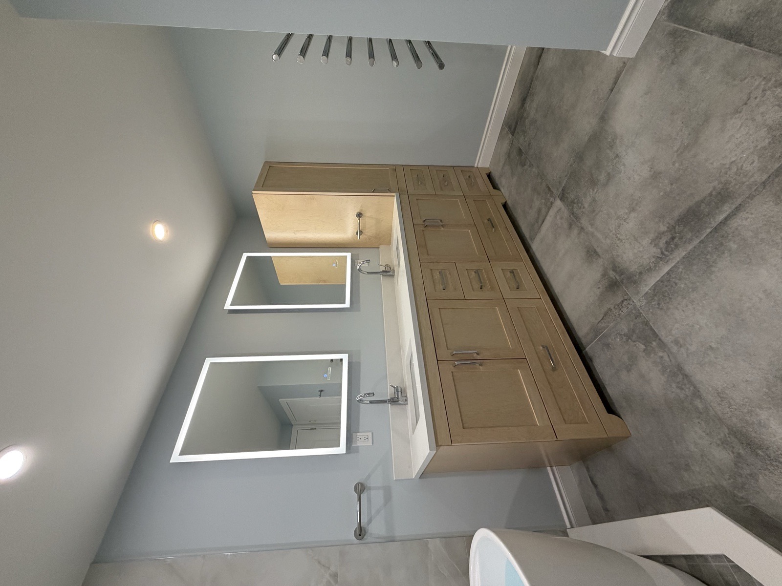 Light-maple custom double vanity with two LED mirrors and a tall built-in linen closet, quartz countertop, and a heated towel rack in a Mississauga bathroom