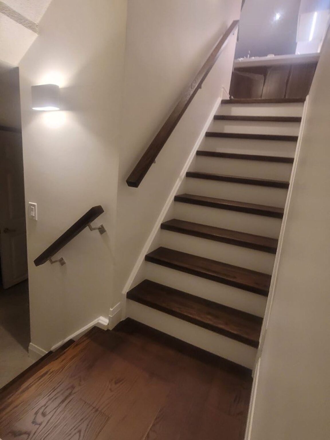 Basement staircase with new oak treads and handrail after renovation.